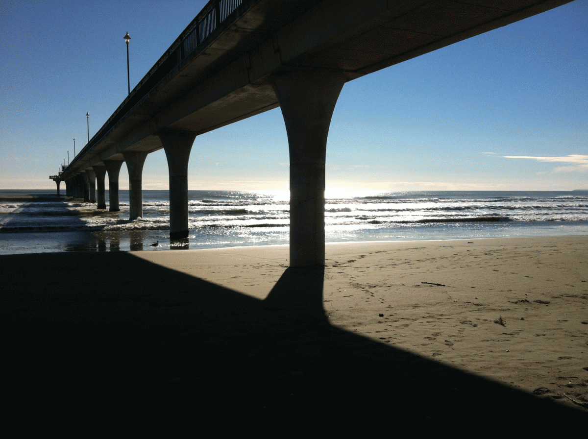 Brighton pier on a sunny day, image taken from the beach under the pier towards the ocean